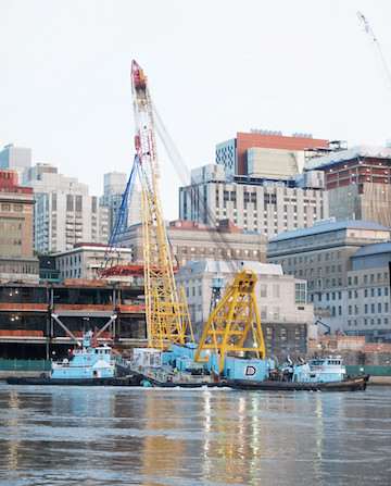 Rockefeller University’s Two-Acre Expansion Sails Up the East River 4 A daytime shot of the crane, with the modules already inserted just ahead of the crane and the FDR Drive at the green fencing level just above the river. | FRANK FARANCE