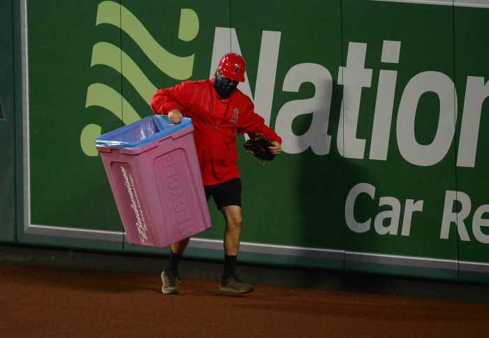A stadium worker removes a trash can that was thrown onto the field during the eighth inning at Angel Stadium.