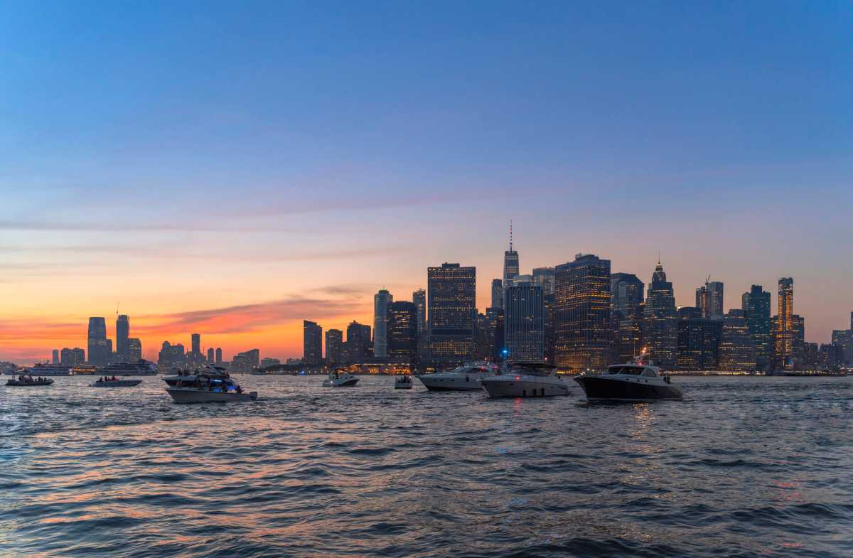 Many yachts on the East River in front of Manhattan Downtown at sunset.