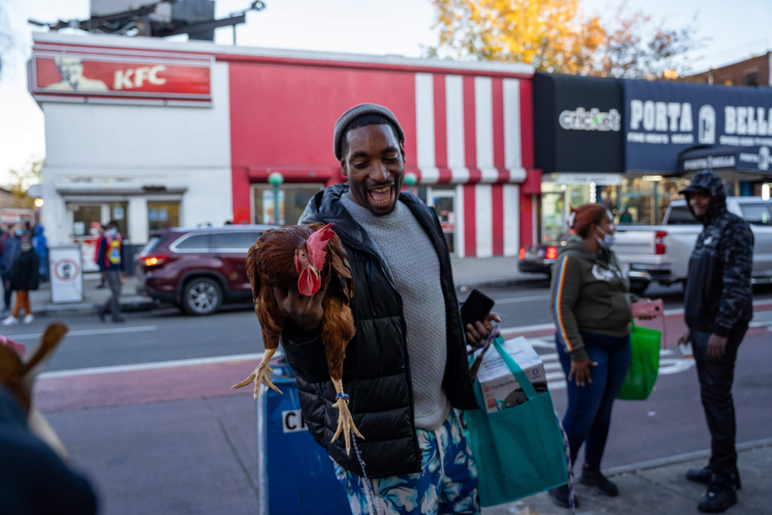 A man is seen walking down Nostrand Ave with a live chicken