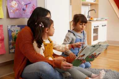 Preschoolers read a picture book with an instructor.