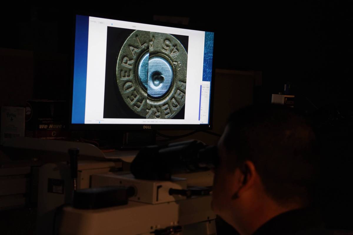 A detective uses a microscope to compare fired bullets
