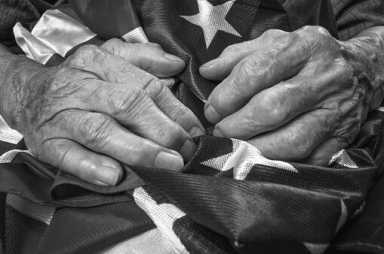 Old woman's hands holding an American flag.