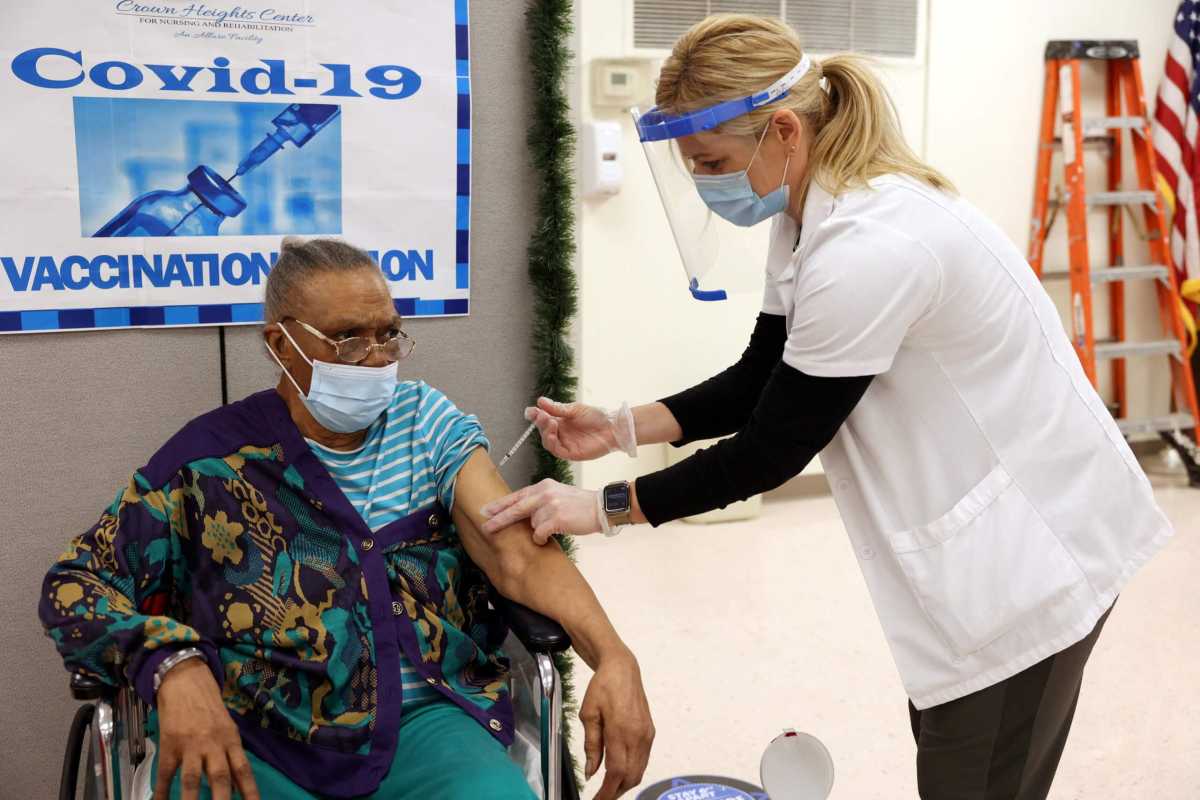 a patient at Crown Heights Center for Nursing and Rehabilitation, a nursing home facility, receives the Pfizer-BioNTech coronavirus disease (COVID-19) vaccine from Walgreens pharmacist Annette Marshall, in Brooklyn