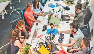 Young co-workers team talking during startup - Happy people planning a new project in creative workplace office - Technology, entrepreneur, marketing and concept - Focus on left man with headphones