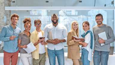 Dream work. Portrait of young and successful co-workers in casual wear smiling at camera while standing in working space