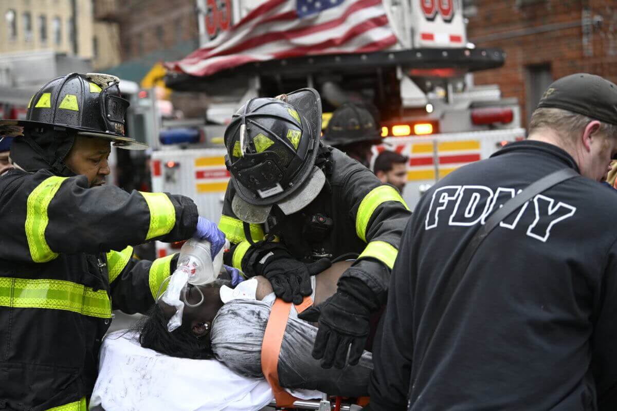 Firefighters administering aid to a victim of a five-alarm inferno in the Bronx