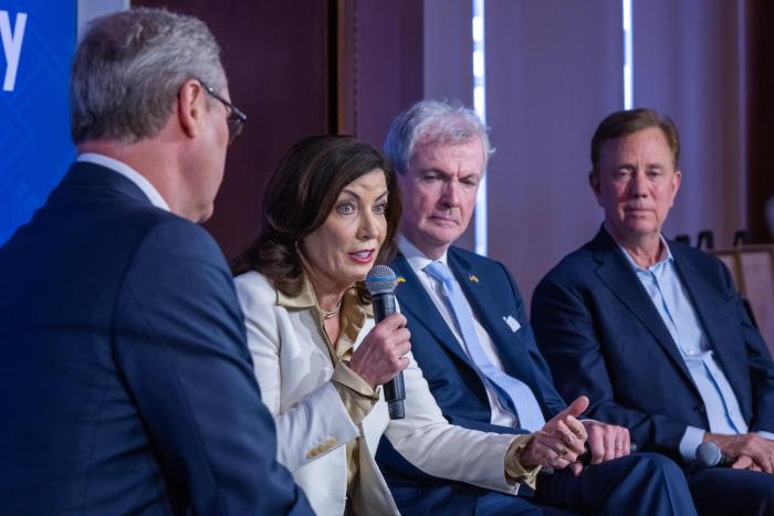 Gov. Kathy Hochul speaks with CT Gov. Ned Lamont (right) at a Regional Plan Association panel, with NJ Gov. Phil Murphy between them