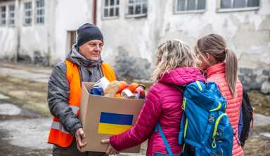 Webinar | Democratizing Philanthropy: You don't have to be a billionaire to give like one 18 Volunteer in orange west gives a box of food donation to fleeing refugees from Ukraine.