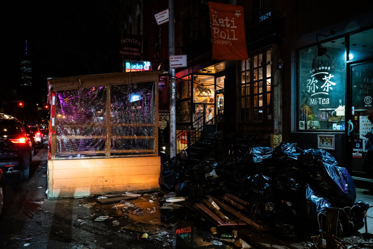 Trash bags pile up next to a dining shed in Manhattan that appears to be used as storage.