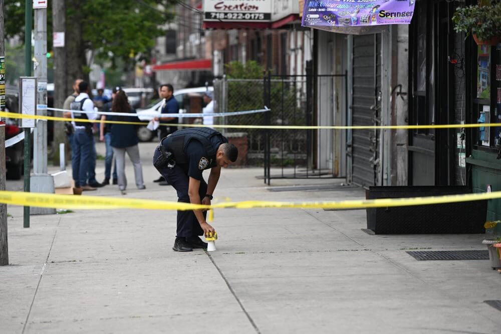 Police canvass the scene of an early afternoon shooting