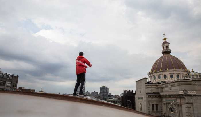 A teen subway surfs on a J train heading into Brooklyn in 2022.