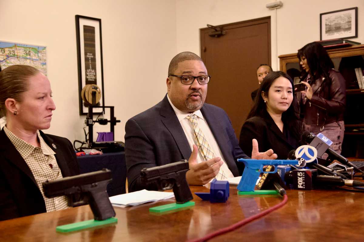 Manhattan DA Bragg at a table with ghost guns on it