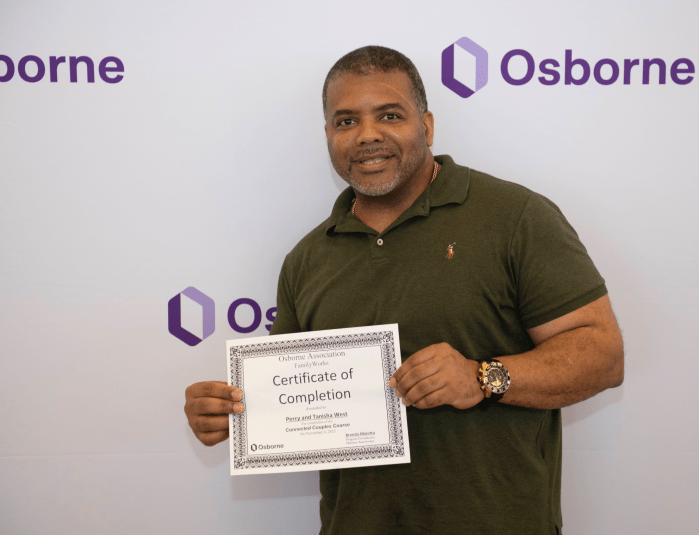 man in green holding a certificate
