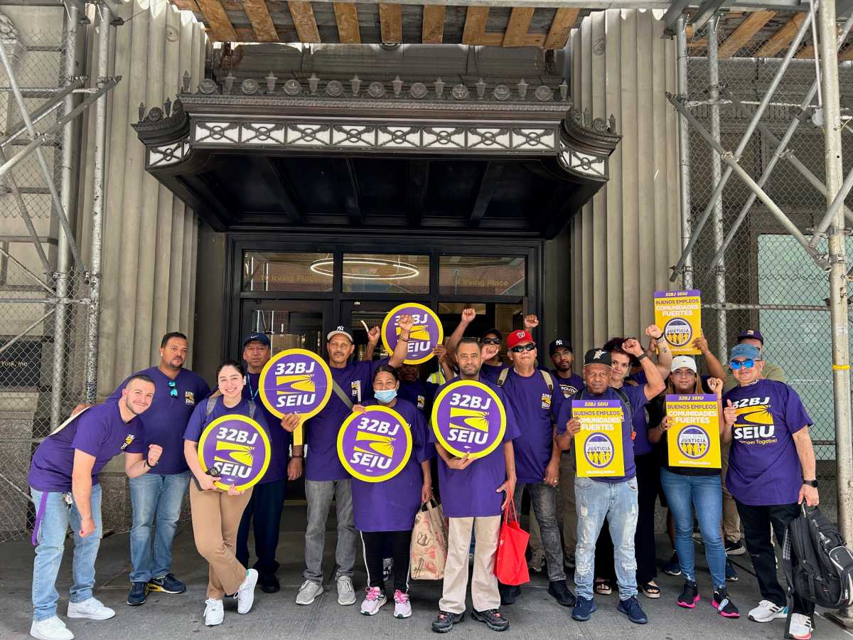 people gathered in front of Con Ed headquarters wearing purple shirts and holding picket signs