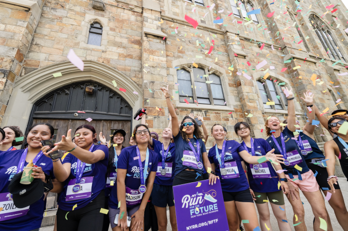 NYPD first deputy commissioner helping high-school girls reach their running milestones at Harlem 5K 2 teenagers wearing purple shirts as the participate in a run