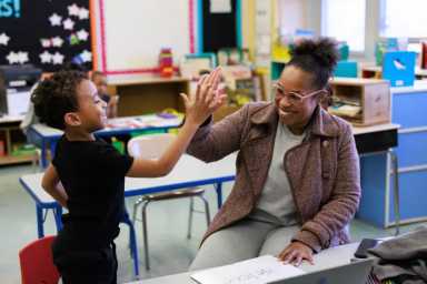 Child and adult high-fiving in a classroom