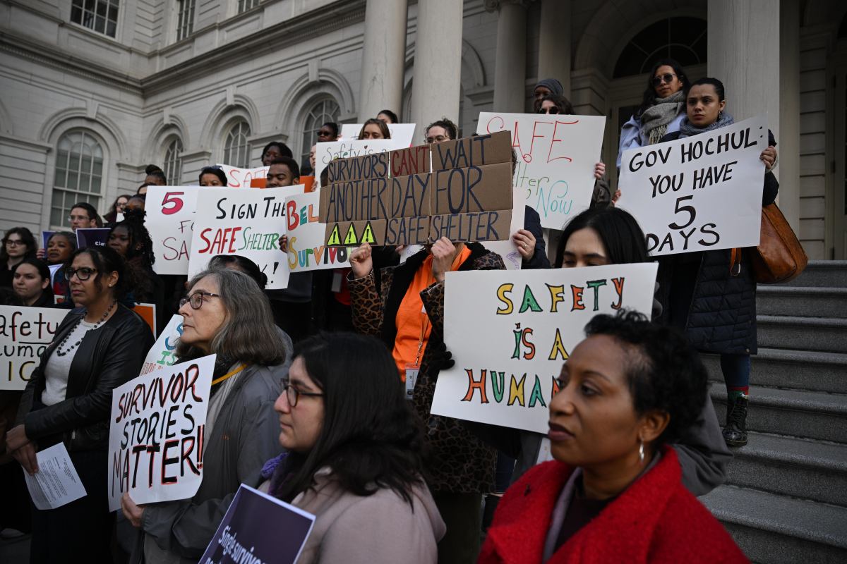 People holding signs reading messages for the passage of the Safe Shelter Act