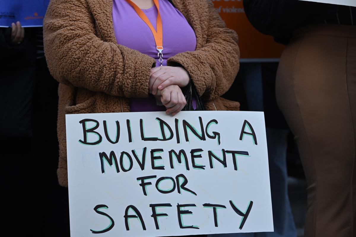 People holding signs reading messages for the passage of the Safe Shelter Act