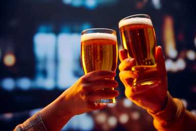 Hands holding lager light foamy big beer glasses