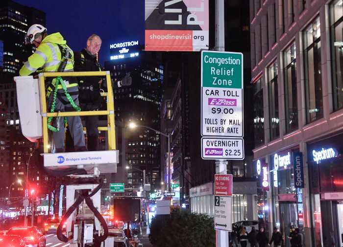 IT'S ON: NYC opens first-in-the-nation congestion pricing toll program in Manhattan 5 two people unveiling a congestion pricing sign at night