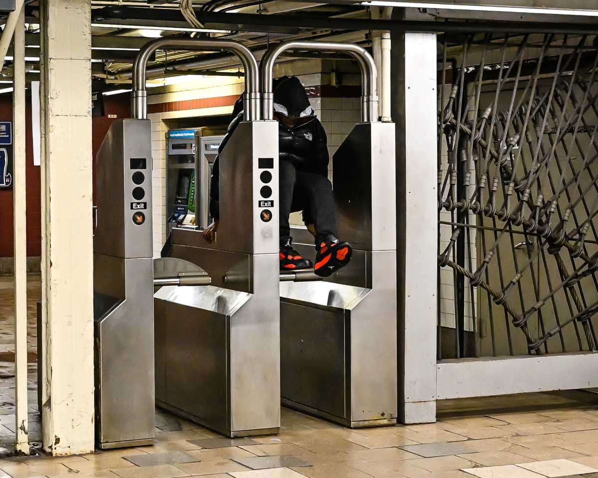 person evading a fare by jumping over a turnstile in an MTA subway station