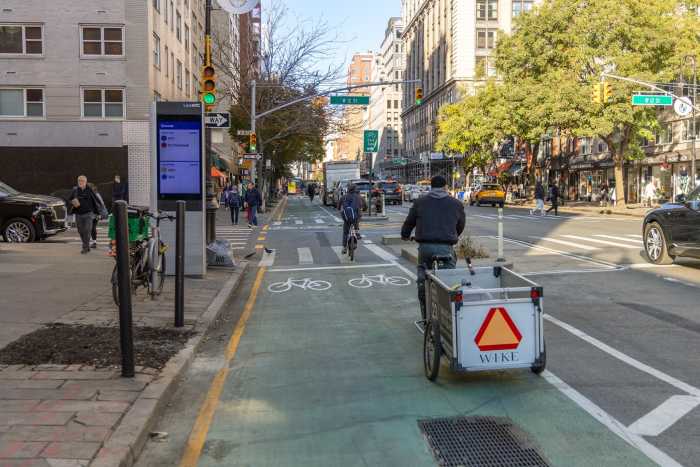 6th Avenue's four-mile protected bike lane corridor completed with addition of Greenwich Village segment 5 Sixth Avenue bike lane during the day with cyclists in it
