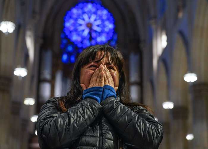 A woman weeps over Pope Francis death while praying at St. Patrick's Cathedral