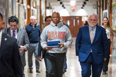 Mayor Adams with officials walking in school hall announcing the NYC budget amid Trump turmoil