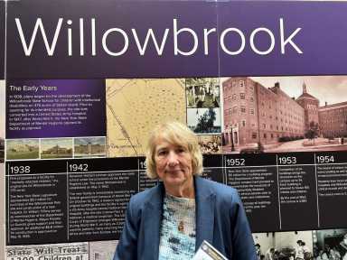 'Never go back!' Hundreds united on Staten Island for 50-year celebration of Willowbrook State School closure decree 11 woman standing in front of exhibit marking history of Willowbrook State School