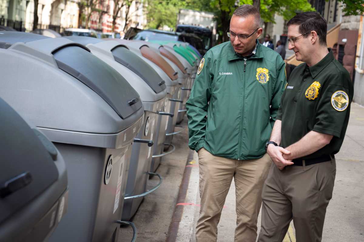 Sanitation workers in West Harlem look at trash containers during containerization