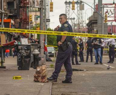 Officer and police tape at scene of shooting near Lower East Side pizzeria.