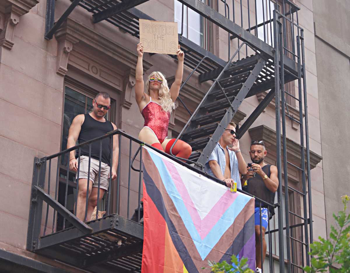 man in leotard holding sign protect the dolls during pride march