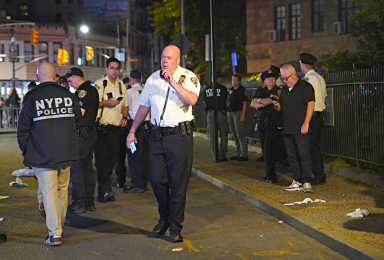 Police officers talking on walkie-talkies and investigating scene of shooting near Stonewall Inn.