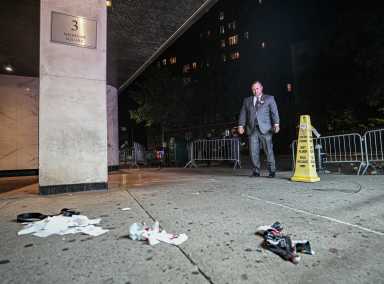 Man in suit looks at crime scene with blood and napkins on sidewalk