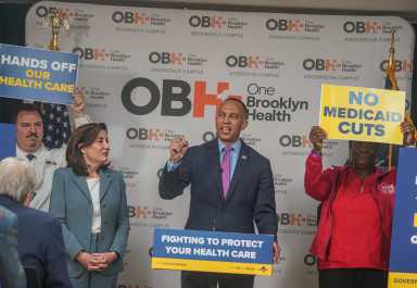 Hakeem Jeffries and Kathy Hochul speak with people holding signs against medicare and medicaid cuts