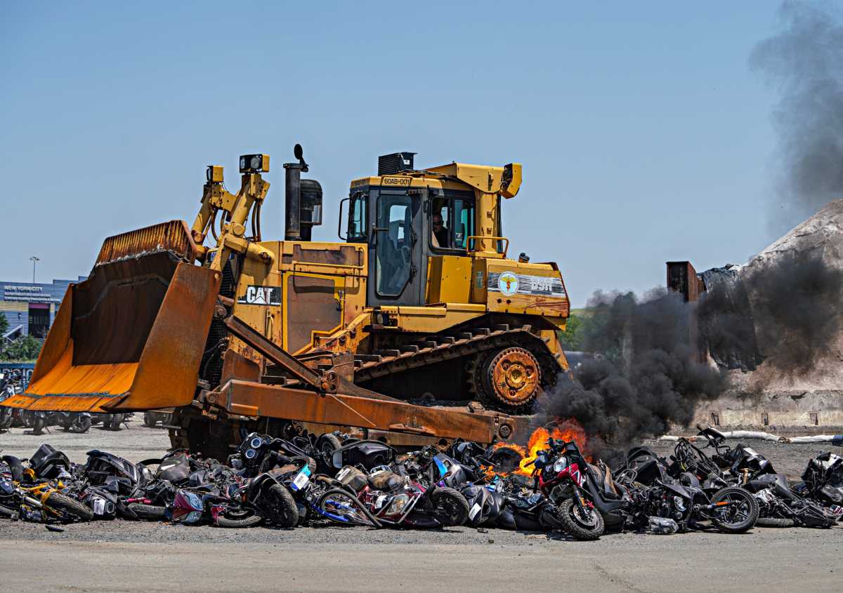 Mopeds crushed and on fire under bulldozer