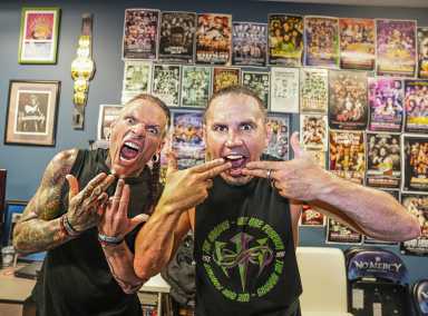 two guys in shirts making finger symbols near mouth