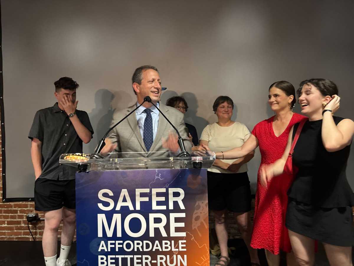 Brad Lander at a podium surrounded by people