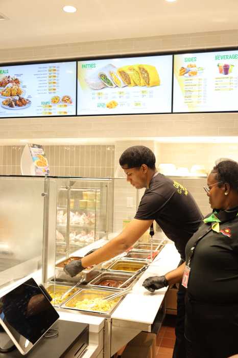 Golden Krust opens at JFK Airport, bringing Caribbean flavors to southwest Queens 2 workers dressed in black serving food