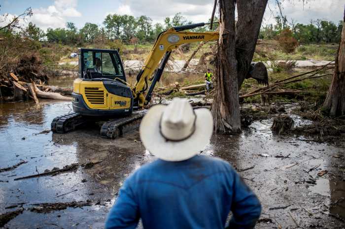 A person watches as machinery is used to clear debris along the banks of the Guadalupe River after catastrophic floods in Center Point, Texas, U.S., July 11, 2025. REUTERS/Sergio Flores TPX IMAGES OF THE DAY