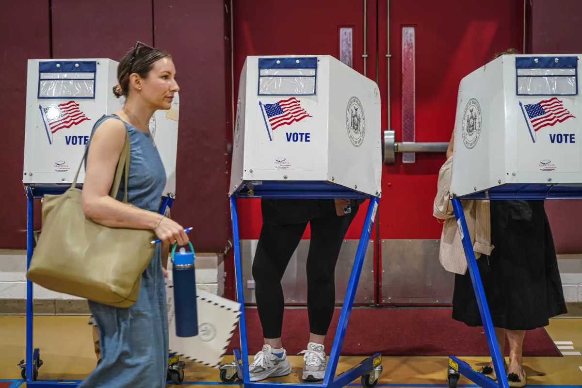 woman walking past people voting in booths on election day in NYC mayor's race