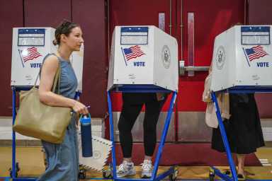 In an already bizarre NYC mayor's race, is there any chance of a write-in candidate finding success? 19 woman walking past people voting in booths on election day in NYC mayor's race