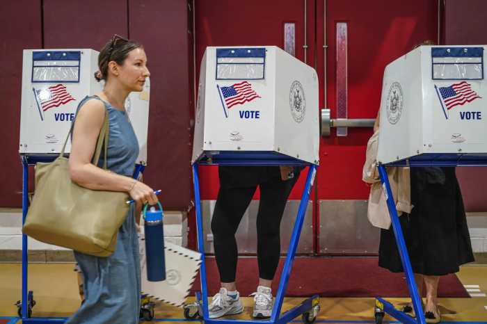 woman walking past people voting in booths on election day in NYC mayor's race