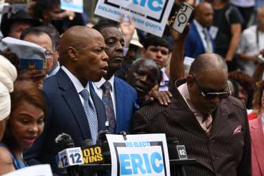 Mayor Eric Adams speaking in suit and tie at podium