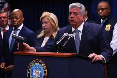 man at podium holding gun while others look on