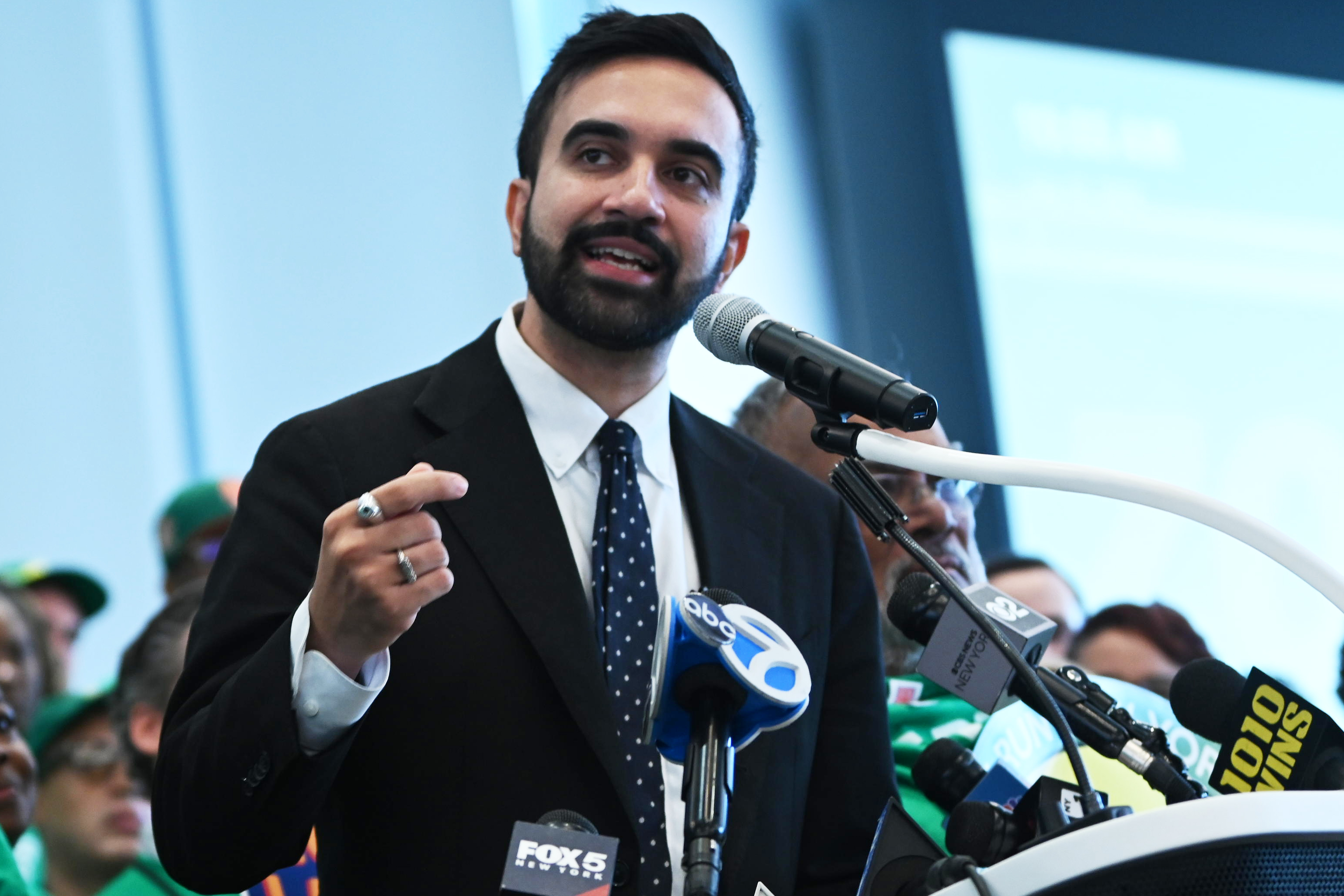 NYC Mayor's Race: How each candidate plans to approach policing and crime 2 man with beard and suit Mamdani speaking at podium with microphones in front of him
