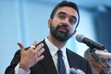 Man with beard and suit talking into microphone