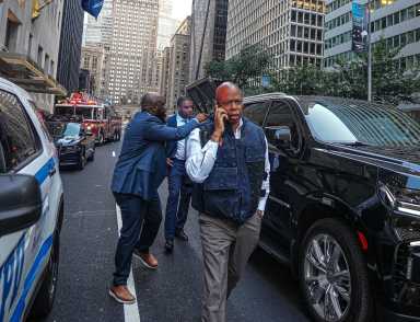 Man on phone in vest talking at crime scene mayor eric adams