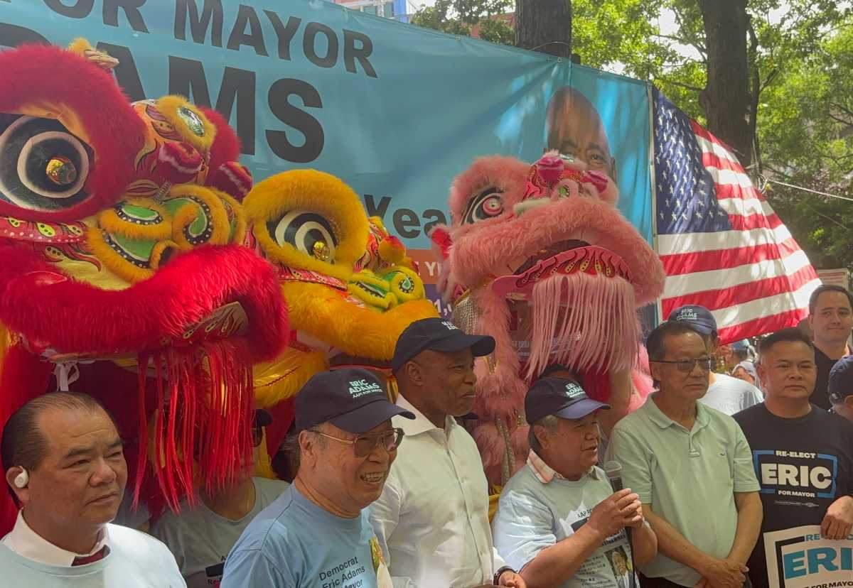 Eric Adams stands with several individuals in front of Chinese dragon dancers.